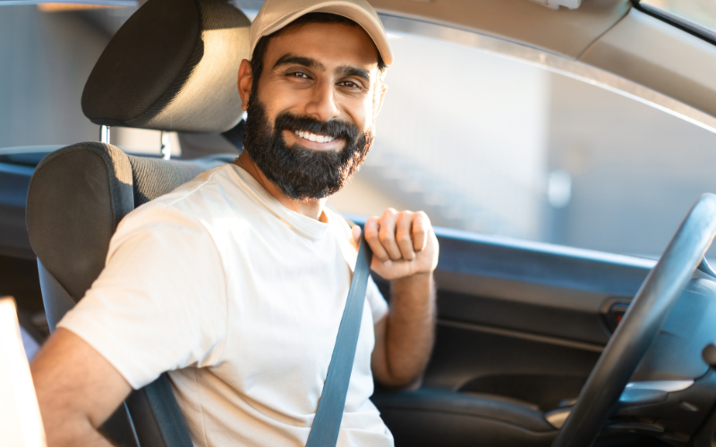 A man smiling behind the wheel of a car